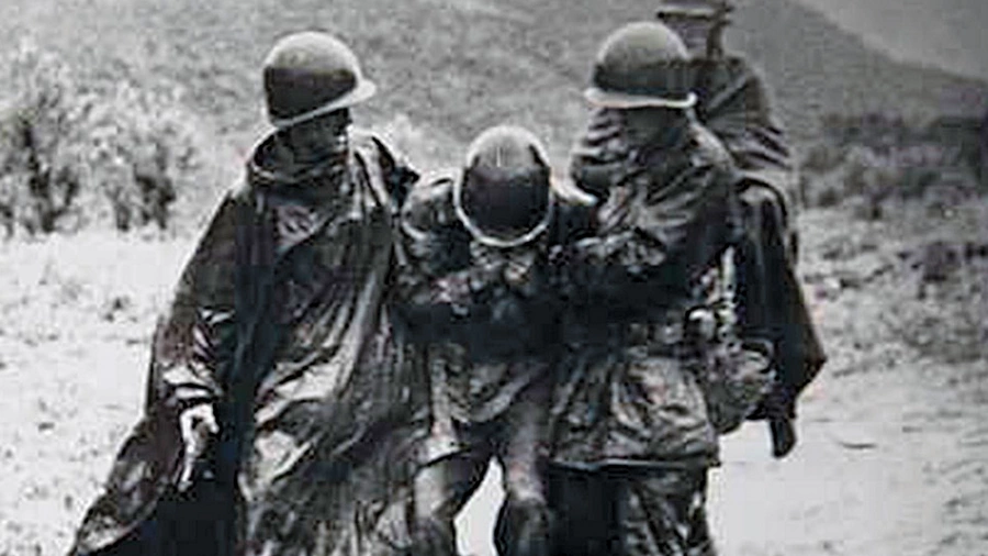 Father Kapaun and Capt. Jerome A. Dolan help an exhausted soldier off the battlefield in Korea, early in the war.