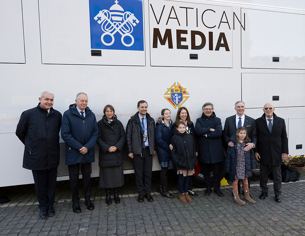 Supreme Knight Patrick Kelly (second from right) and his family stand with staff of the Dicastery for Communication, including prefect Paolo Ruffini (third from right), and Enrico Demajo (right), director of the Knights of Columbus office in Rome, outside the dicastery&rsquo;s new mobile broadcasting unit in Rome on Dec. 21. 