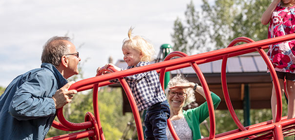 Grandparents in a park playing with their grandchild.
