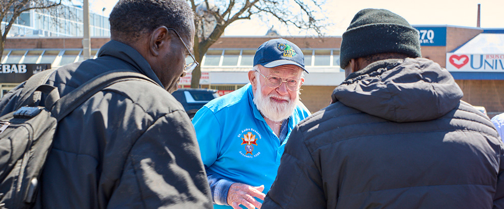 Bill Graham (center) of Our Lady of Mount Carmel Council 12706 in Mississauga, Ontario, greets visitors at one of the Free Food Tables supported by the council on April 8. (Photo by Nadia Molinari)