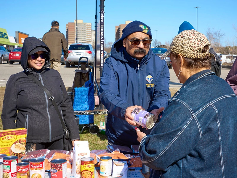 District Deputy Trevor Phillips of Our Lady of Mount Carmel Council 12706 in Mississauga, Ontario, assists a woman at one of the Free Food Tables supported by the council on April 8. (Photo by Nadia Molinari)