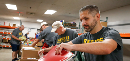 Edward Domich (right) and other members of Siena Council 8596 in West Dundee, Ill., fill backpacks with school supplies for families in need. The items were collected during the council’s annual drive with F.I.S.H. Food Pantry, totaling more than 500 pounds — enough to fill more than 75 backpacks. (Photo by Karen Callaway)