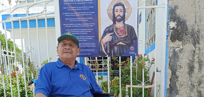 Juan Huchim-Tun, a member of Mons. Lazaro Perez Jimenez Council 17543 in Mérida, Mexico South, sits by one of several banners of Christ the Worker that the council hung near Cristo Obrero Parish.