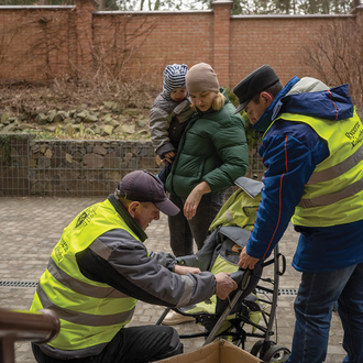Knights assist a mother and baby with a new stroller at the archdiocesan pastoral center in Lviv.