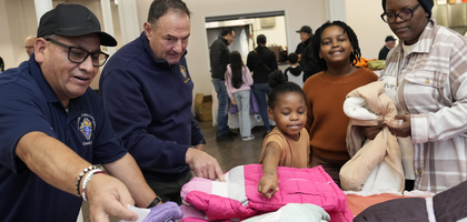 Nelson Guzman (left), a member of Todos Los Santos Council 38 in Bridgeport, Conn., and Steve Trifone, a member of Santa Fe Council 2978 in Cheshire, help 7-year-old Amahle choose a winter coat during a Coats for Kids distribution at All Saints Parish in Waterbury.