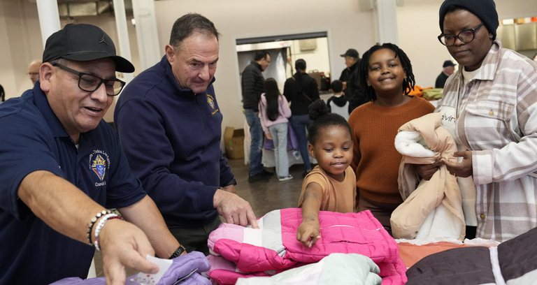 Nelson Guzman (left), a member of Todos Los Santos Council 38 in Bridgeport, Conn., and Steve Trifone, a member of Santa Fe Council 2978 in Cheshire, help 7-year-old Amahle choose a winter coat during a Coats for Kids distribution at All Saints Parish in Waterbury.