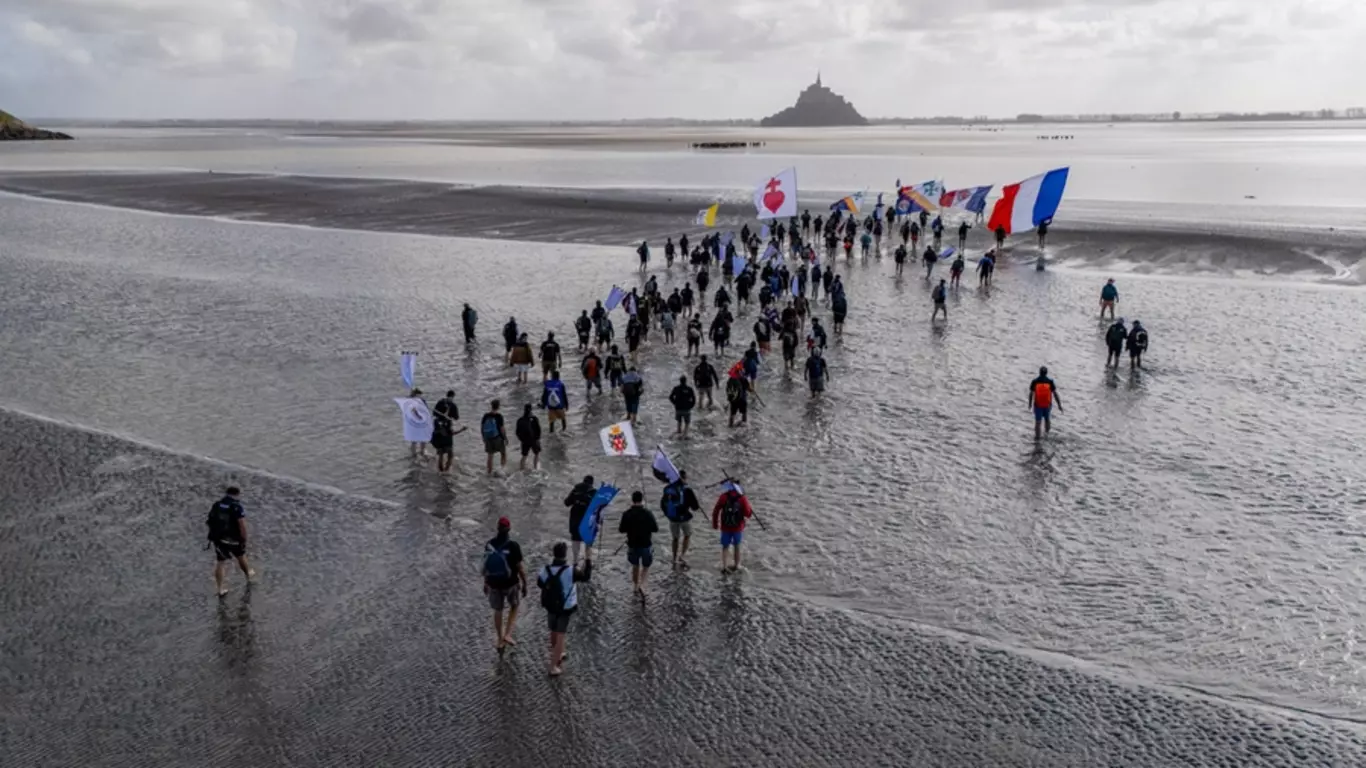 Carrying the flags of their country, the Vatican and the Order, Knights in France embark on an 8-mile walk across the shallow bay between the Normandy coast and Mont Saint-Michel, home to the Catholic abbey of the same name.