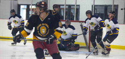 Several Knights dressed in hockey equipment play a game of ice hockey in an indoor ice rink.