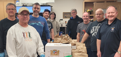 Members of Holy Family Council 10797 in Regina, Saskatchewan, gather around 60 bagged lunches they prepared for Carmichael Outreach, a local shelter for people experiencing homelessness. 