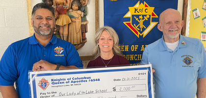 Grand Knight Clyde Straub (right) and Deputy Grand Knight Steven Sandoval of Queen of Apostle Council 6548 in Houghton Lake, Mich., present a $2,000 check to Principal Michelle Johnson of Our Lady of the Lake Regional Catholic School. 