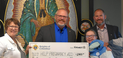 Grand Knight Steven Kolenda (center) and Financial Secretary Jason Bargenquast of Sacred Heart of Jesus Council 13641 in Grand Rapids, Mich., present a $2,900 check — proceeds from the council’s annual Baby Bottle Boomerang — and coats to Paula Veneklase, director of HELP Pregnancy Aid. The council donated two cases of coats through the Knights of Columbus Coats for Kids program. An additional $400 donation was made by the Supreme Council through the ASAP (Aid and Support After Pregnancy) program.