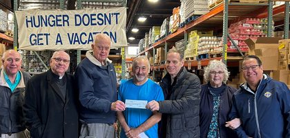 Knights from St. Mary’s Stony Hill Council 14675 in Watchung, N.J., and Msgr. William Benwell (third from left), pastor of St. Mary Parish and council chaplain, present a check for $15,600 to Steve Katz (middle, blue shirt), executive director of Food Bank Network, and office manager Paulette Adam. Since November 2021, the council has donated $50,000 to the food bank.