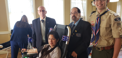 Giuseppe Petruso (left) and Grand Knight Frederick Bedell Jr. of St. Anastasia Council 5911 in Little Neck, N.Y., and Assistant Scoutmaster Alexander Hom of Scout Troop 153 in Douglaston stand with Johanna Barrett as she donates blood during a recent drive hosted by Council 5911 at St. Anastasia Parish.