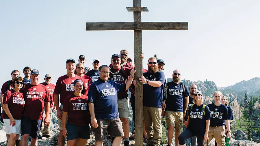 K of C pilgrims stand with the cross they carried to the summit of Black Elk Peak to honor the Lakota holy man and pray for his canonization and intercession.