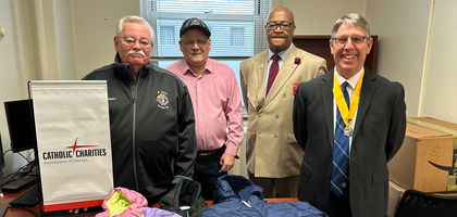 Knights from Chicago St. Cabrini Council 182 assemble behind some of the winter jackets donated by the council to Catholic Charities of the Archdiocese of Chicago through the Knights of Columbus Coats for Kids program. 