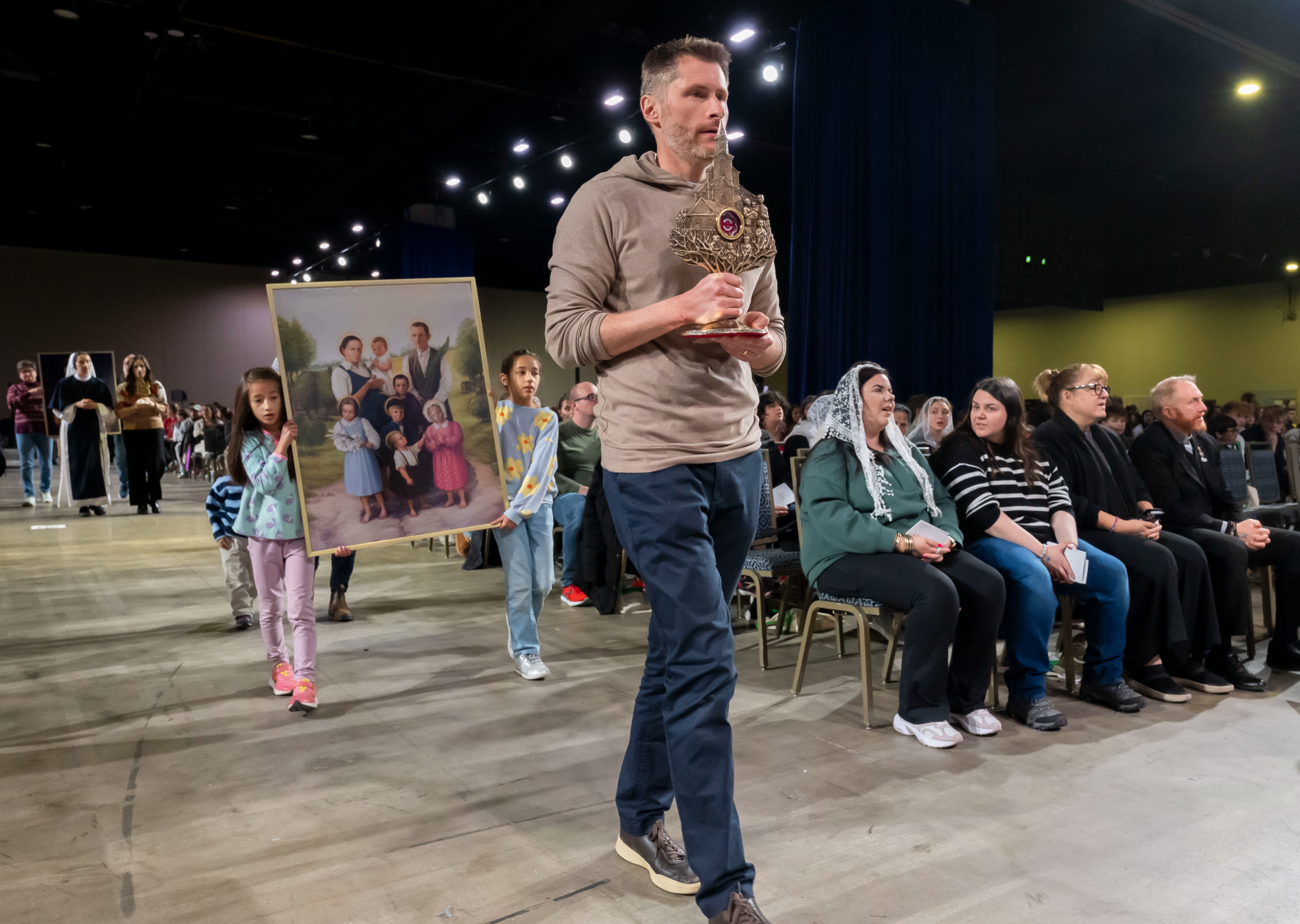 A family processes with relics and an image of the Ulma family during Life Fest at the Gaylord National Resort and Convention Center in Oxon Hill, Md.