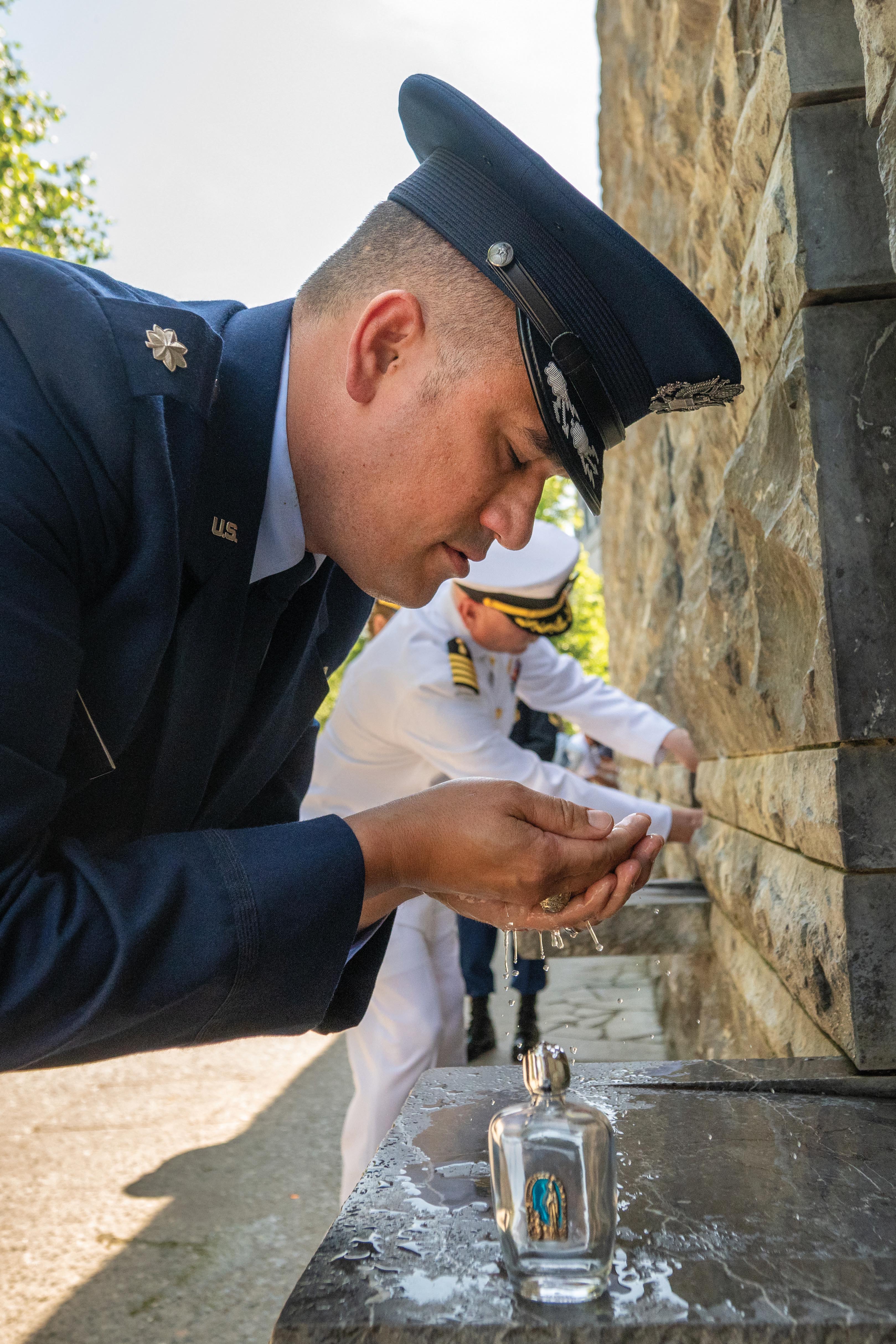 Service members collect holy water from the spring discovered by St. Bernadette Soubirous. 