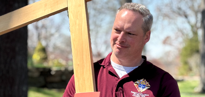 Deputy Grand Knight Mark Ludwig of St. Matthew Council 14360 in Norwalk, Conn., carries a cross during an outdoor Stations of the Cross at St. Matthew Parish on Good Friday.