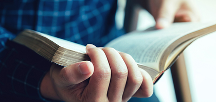 A close up of a man's hand holding a bible.