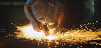 A man hits an anvil with a hammer and sparks explode.