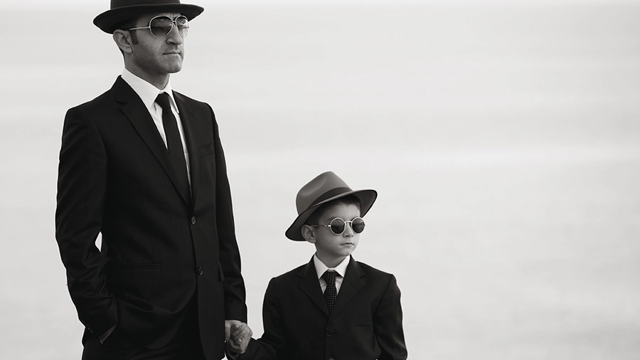 A boy holds his father's hand.