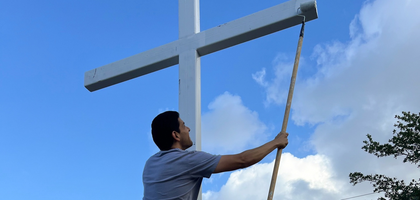 Mario Perez, a member of St. Monica Council 12880 in Miami Gardens, Fla., paints a stainless steel cross at the entrance of St. Monica Church.