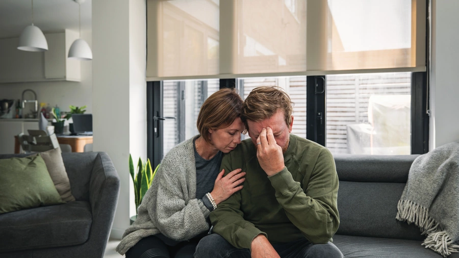 A married couple looks stressed on a couch.