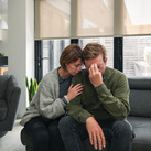 A married couple looks stressed on a couch.