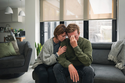 A married couple looks stressed on a couch.