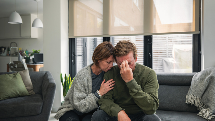 A married couple looks stressed on a couch.