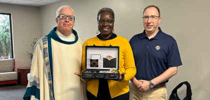 Grand Knight Nicholas Andersen (right) and Father John Vallier, chaplain of Bishop Haas Council 4362 in Wyoming, Mich., present a Mass kit to Sienna Mavima, a parishioner of St. John Vianney Catholic Church who will personally deliver the kit to a local priest during a visit to Zimbabwe.