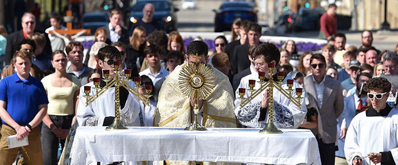 Father Enan Zelinski kneels before the Blessed Sacrament as he leads Benediction outside the state capitol in Madison, Wis.