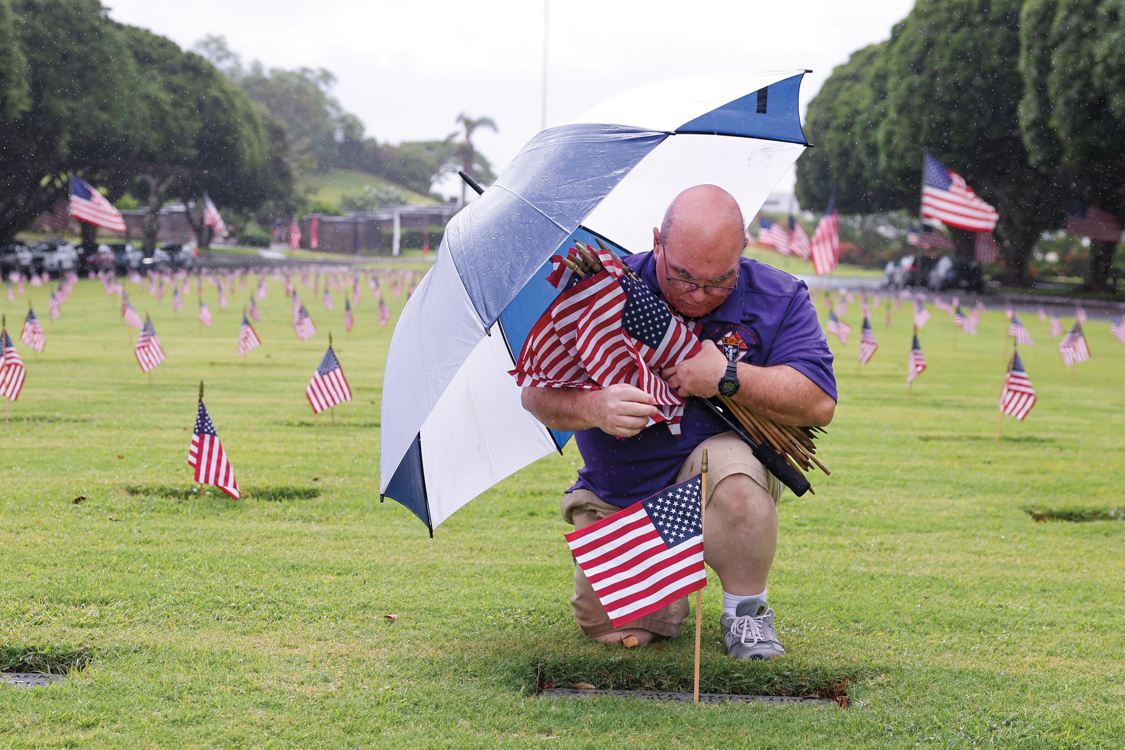 A Knight  prays after placing a flag at the grave of a fallen service member at the National Memorial Cemetery of the Pacific (Punchbowl) in Honolulu, Hawaii.