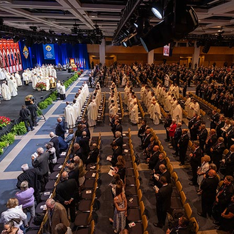Knights and their families dressed in formal attire stand in an auditorium for the Memorial Mass of the 142nd Supreme Convention on Aug. 8 in Québec City.