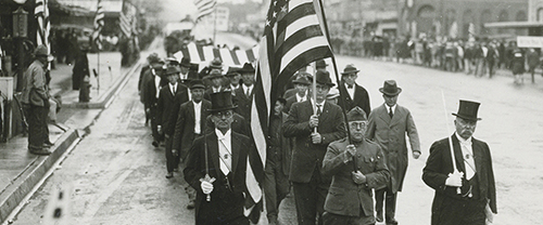 A flag bearer wearing an American Expeditionary Forces uniform leads a Fourth Degree honor guard in the Armistice Day Parade in Taylor, Texas.