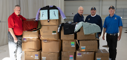 Members of Msgr. John R. McGinley Council 1170 in Stevens Point, Wis., stand next to some of the new winter coats donated by the council to an Operation Bootstrap coat distribution at Stevens Point Airport.