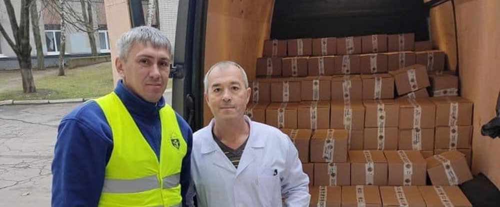 Men standing in front of a van with boxes