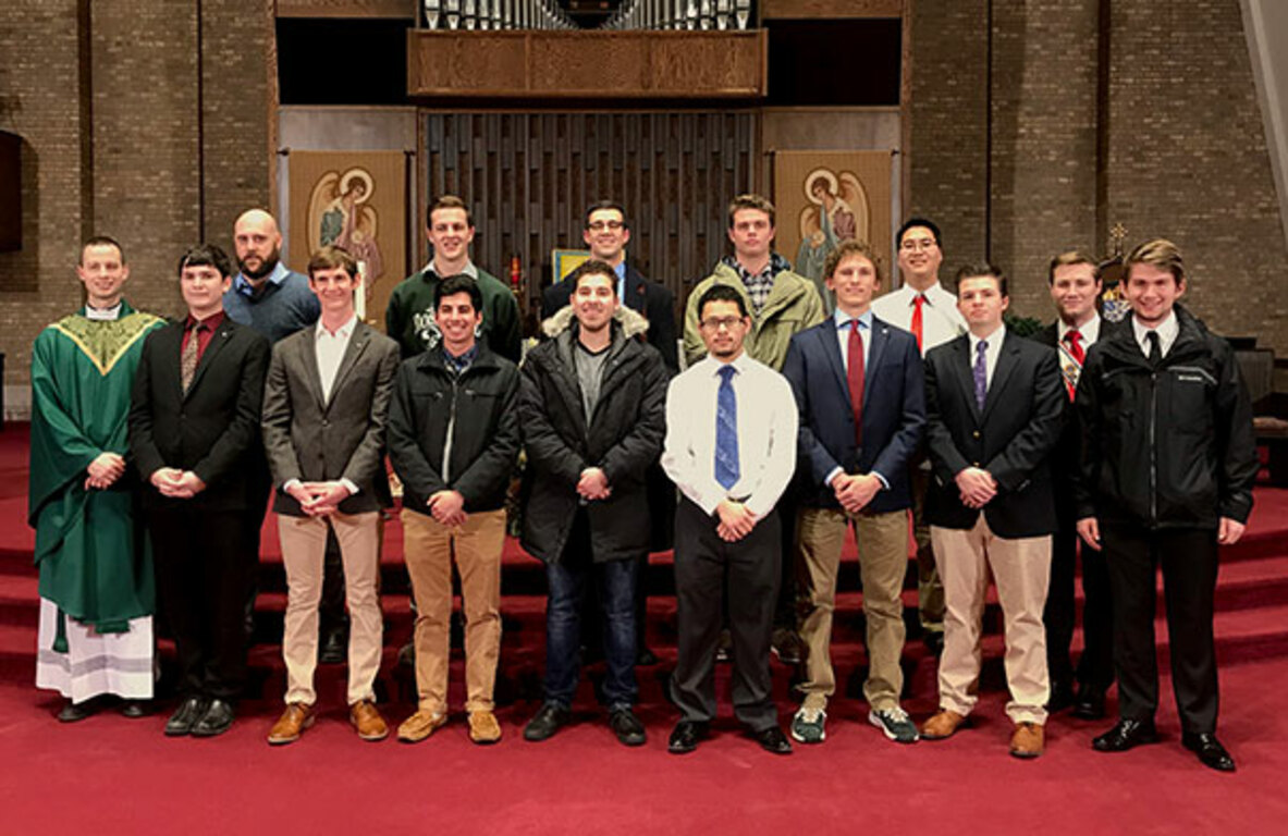 College knights standing in front of an altar with their priest.