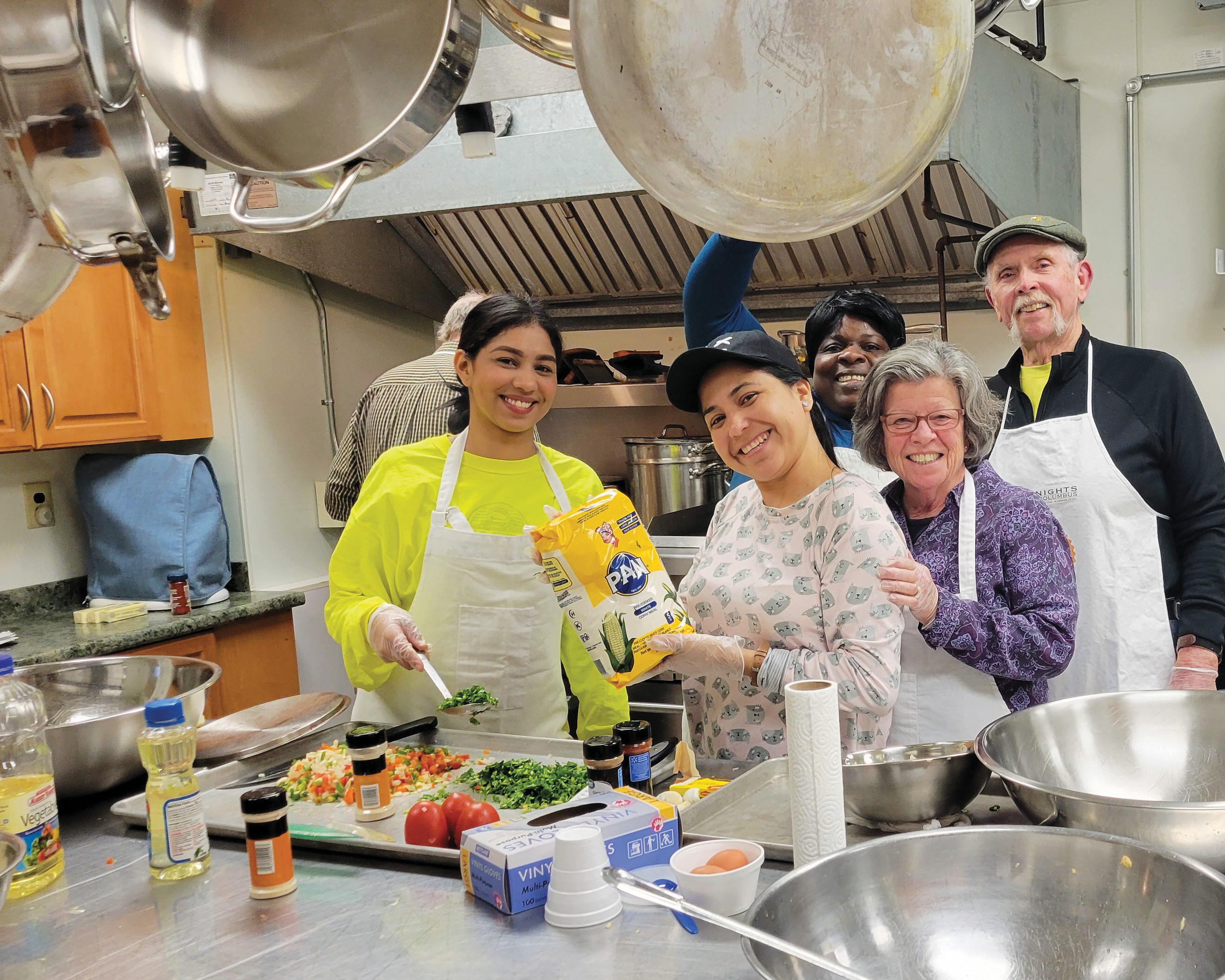 Jack McCarthy (right) of St. Edward the Confessor Council 15972 in Westminster, Mass., and others cook dinner for 30 migrant families from South America and the Caribbean.