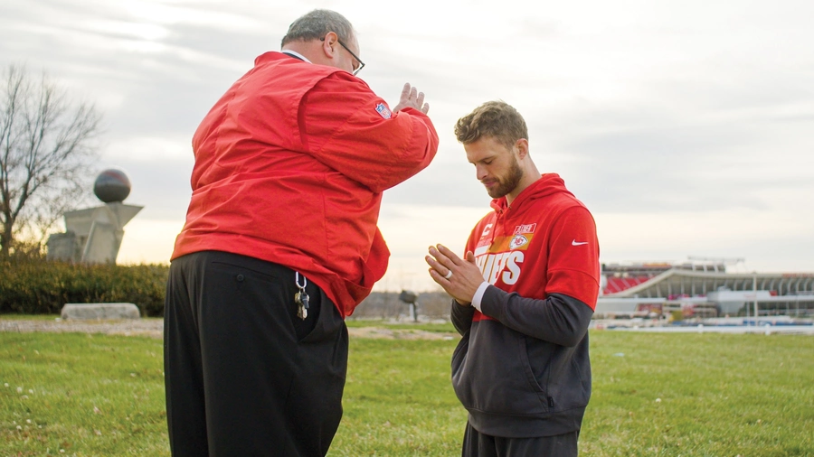 Father Richard Rocha gives a blessing to Chiefs kicker Harrison Butker