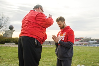 Father Richard Rocha gives a blessing to Chiefs kicker Harrison Butker
