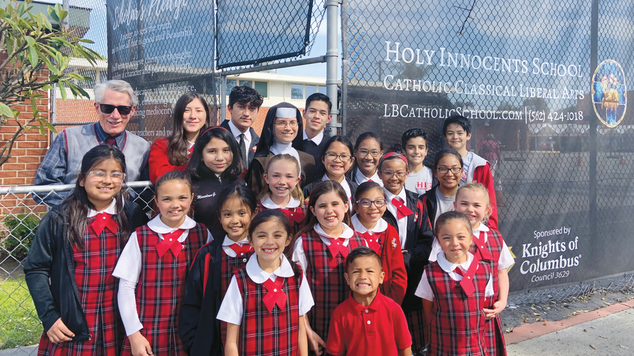 Students and staff members of Holy Innocents School stand before custom-printed fencing screens donated by Msgr. John Cawley Council 3629 in Lakewood, Calif., in 2022.