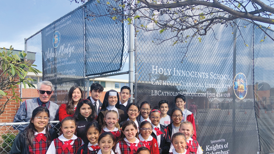 Students and staff members of Holy Innocents School stand before custom-printed fencing screens donated by Msgr. John Cawley
Council 3629 in Lakewood, Calif., in 2022. The screens provide much-needed privacy to the playground of the school, which is
located in a busy urban neighborhood in Long Beach.
