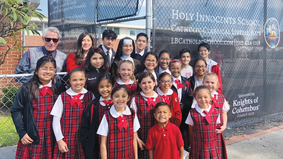 Students and staff members of Holy Innocents School stand before custom-printed fencing screens donated by Msgr. John Cawley Council 3629 in Lakewood, Calif., in 2022.