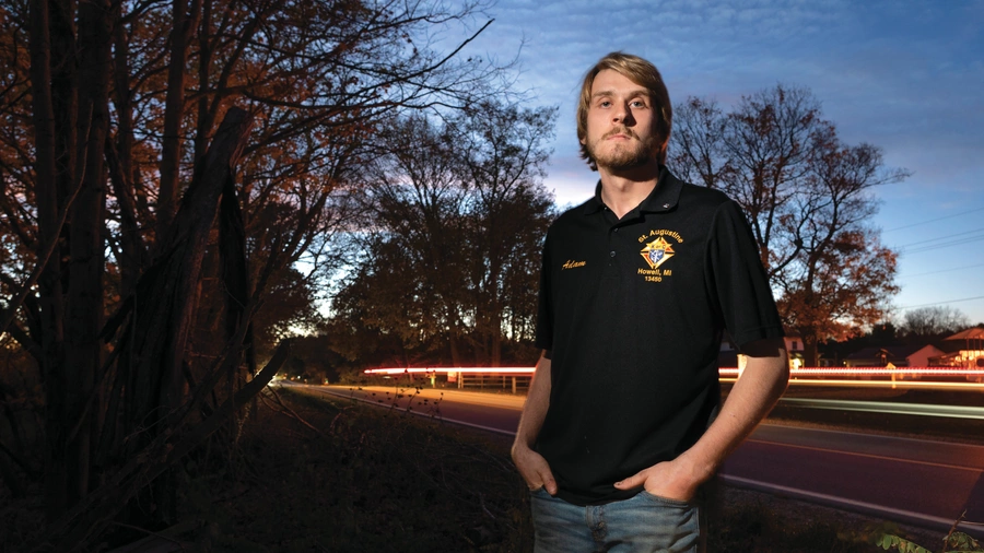 Adam Parzuchowski, 21, stands at the site where he rescued a man from a burning vehicle in June. 