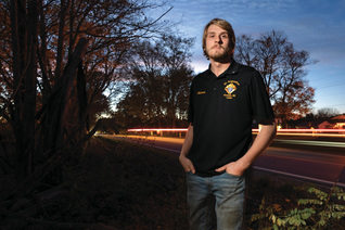 Adam Parzuchowski, 21, stands at the site where he rescued a man from a burning vehicle in June. 