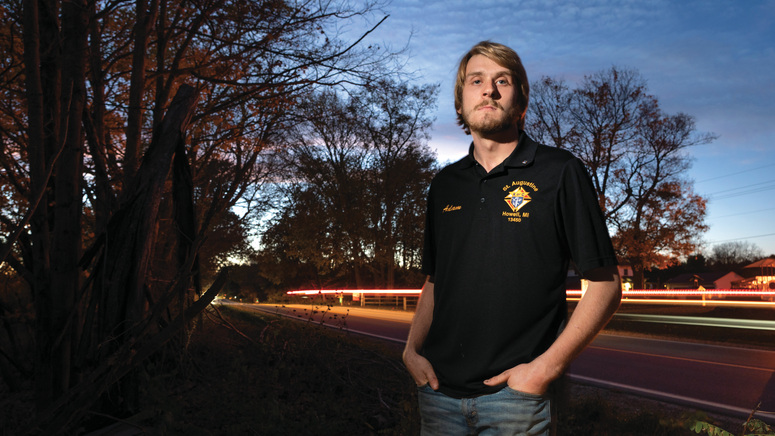 Adam Parzuchowski, 21, stands at the site where he rescued a man from a burning vehicle in June. 