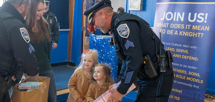 Officers from the Woonsocket Police Department accept toy donations from a family during the annual toy drive hosted by the department in collaboration with Woonsocket (R.I.) Council 113. Organized since 2009, the drive honors Ron Auger, a police dispatcher and son of a Knight, who died that year. The 2025 campaign collected 1,500 toys for 300 local children. (Photo by Bryce Vickmark)
