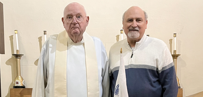 Father Walter Ciesla, pastor of St. Stanislaus Kostka Parish in Michigan City, Ind., and Jim Gallas, a fellow member of St. Stanislaus Kostka Council 18574, stand behind a display honoring four U.S. Army chaplains —a Catholic priest, Jewish rabbi and two Protestant ministers — who gave their life jackets to save others aboard the USS Dorchester when it was torpedoed on Feb. 3, 1943. 