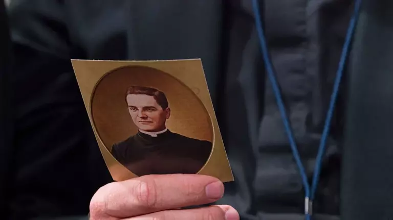 A Catholic priest holding father McGivney’s photo